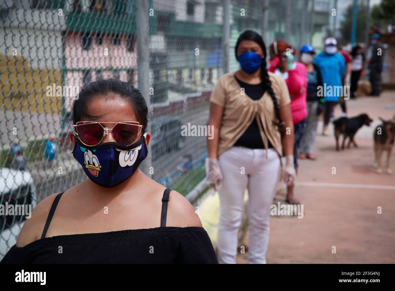 Während der Coronavirus-Krise warten mehrere Frauen in einer Schlange, um Hilfsnahrung zu erhalten.Frauen, die in der Nachbarschaft an den Hängen von Quito-Ecuador leben, erhalten Nahrungsmittelhilfe von der Regierung während der stärksten Momente der Covid-19-Pandemie. Stockfoto