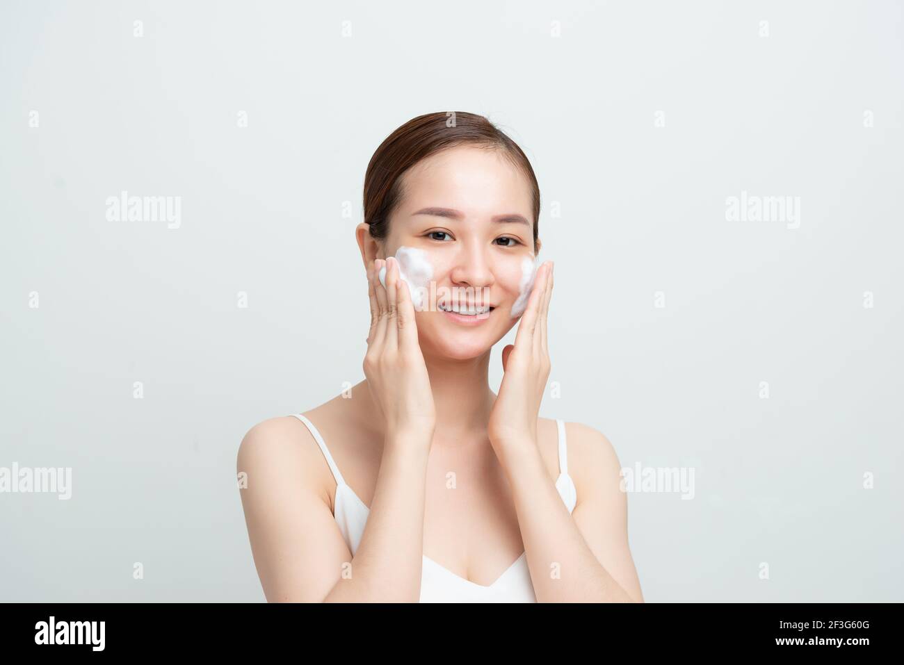 Bild von liebenswert asiatische Frau waschen ihr Gesicht mit Schaum Gesichtsreiniger isoliert auf weißem Hintergrund Stockfoto