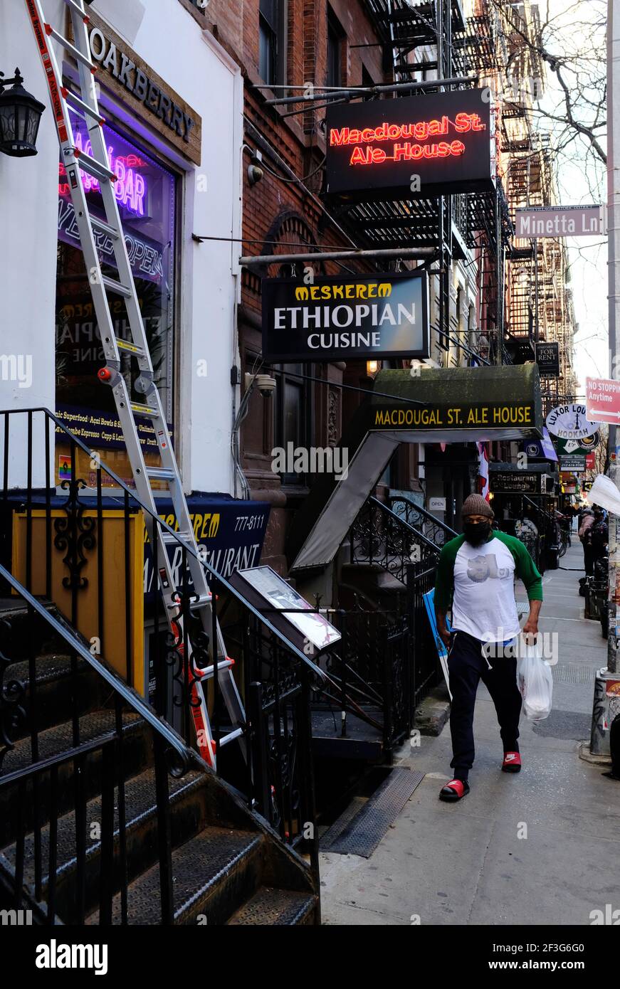 MacDougal Street mit Geschäftsschildern und Mann mit Gesichtsbedeckung.Greenwich Dorf.Manhattan.New York City.USA Stockfoto