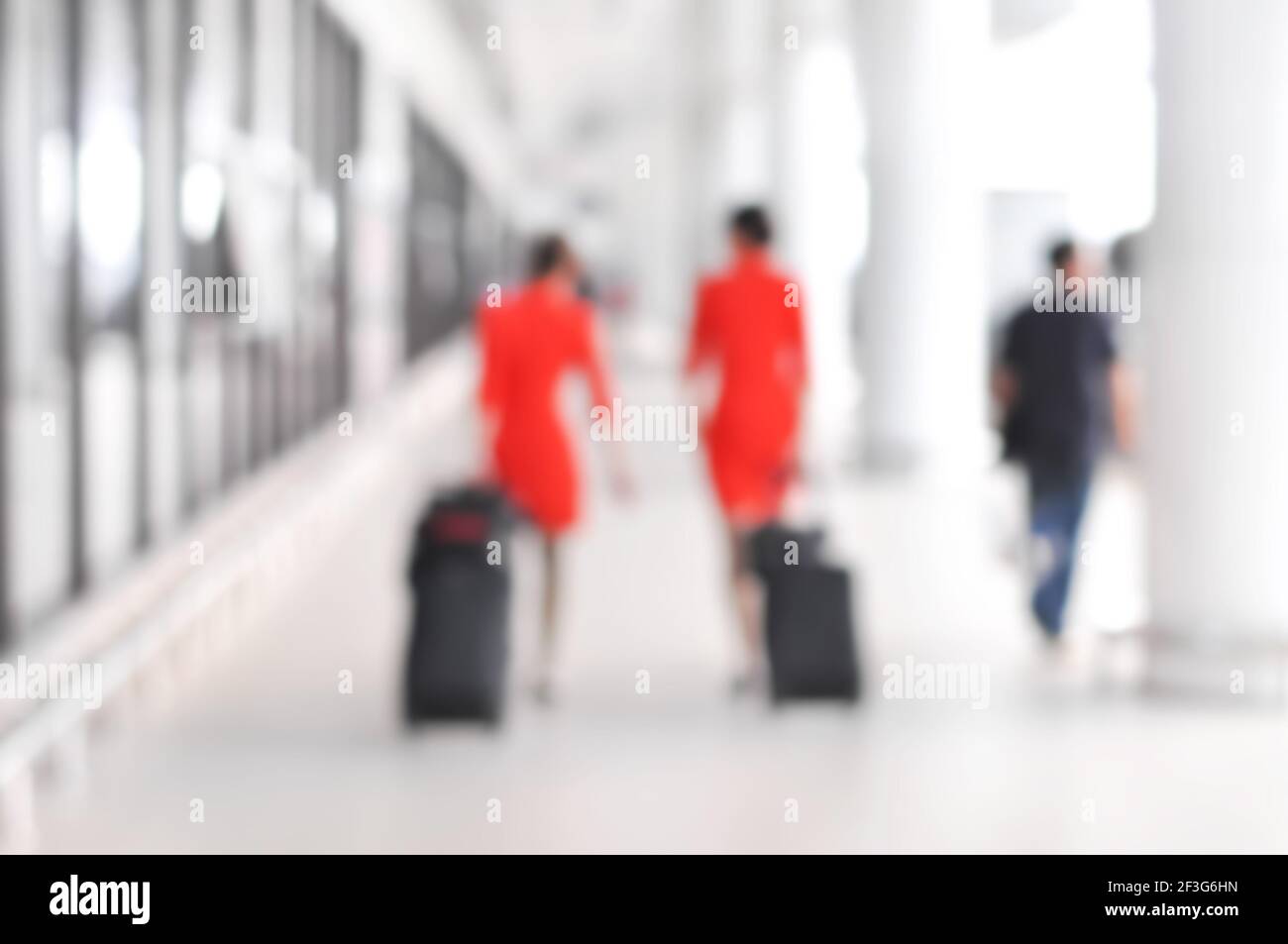 Verschwommene Leute und Flugbegleiter, die auf dem Flughafenflur herumlaufen Stockfoto