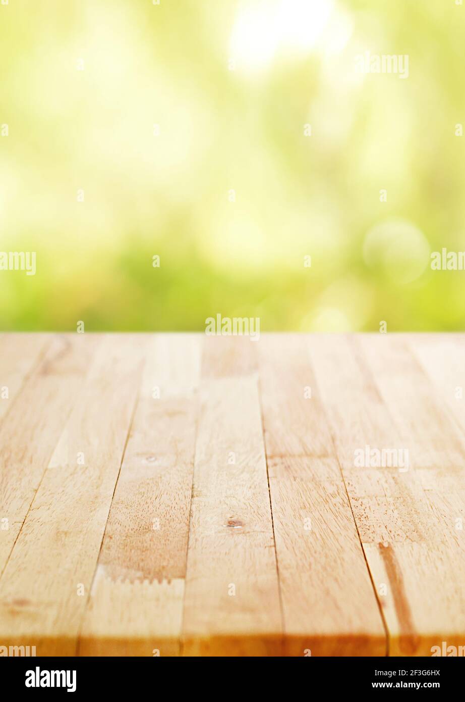 Holztischplatte auf unscharfen grünen Bokeh Hintergrund, Poster Größe Verhältnis - kann für die Montage oder Anzeige Ihrer Produkte verwendet werden Stockfoto