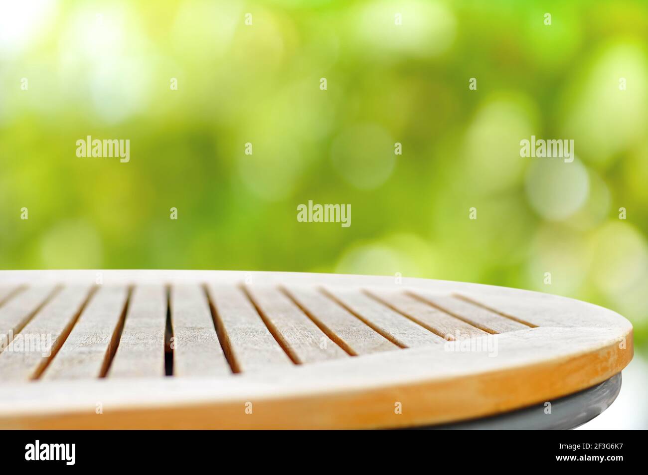 Runde Holztischplatte auf grünem Bokeh abstrakten Hintergrund - Kann zur Anzeige oder Montage Ihrer Produkte verwendet werden Stockfoto