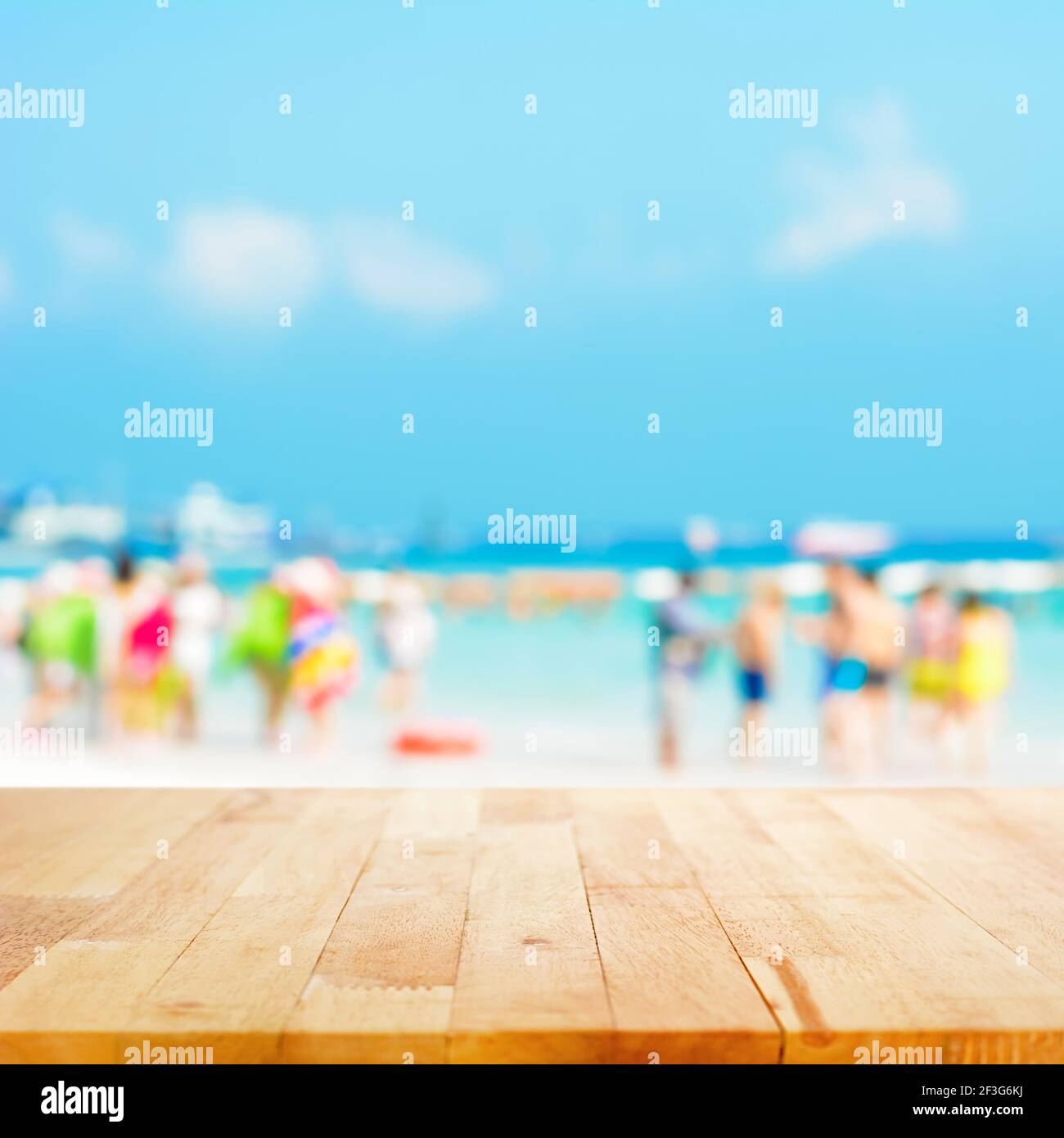 Holztischplatte mit verschwommenen Leuten am Strand Hintergrund - kann zur Anzeige oder Montage Ihres verwendet werden Produkte Stockfoto