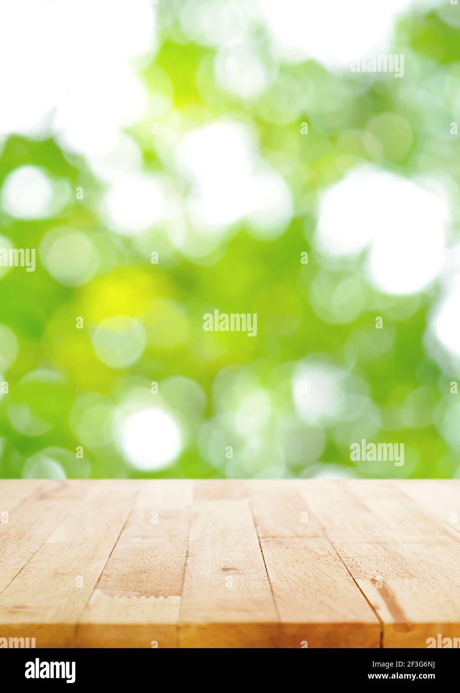 Holztischplatte auf unscharfen grünen Bokeh Hintergrund, Poster Größe Verhältnis - kann für die Montage oder Anzeige Ihrer Produkte verwendet werden Stockfoto