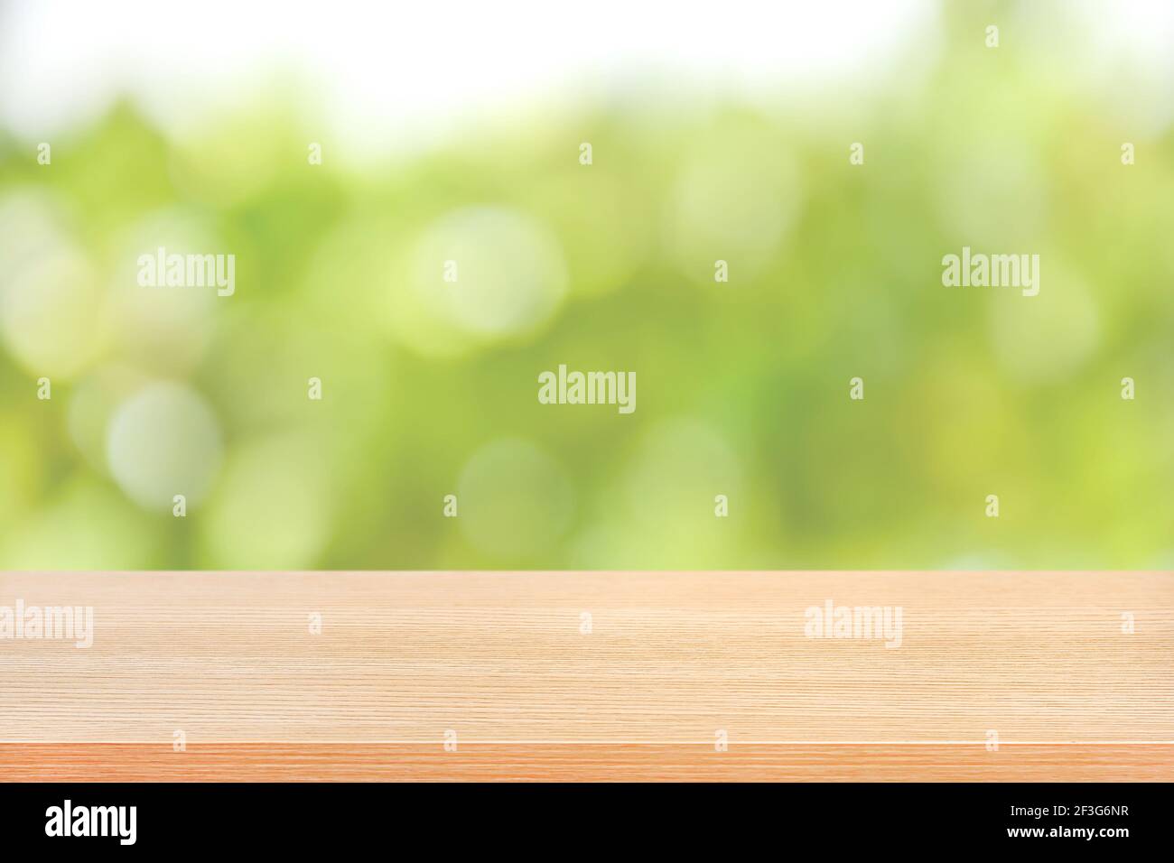 Holztischplatte auf grünem Bokeh abstrakter Hintergrund, weicher Ton - kann für Montage oder Anzeige Ihrer Produkte verwendet werden Stockfoto