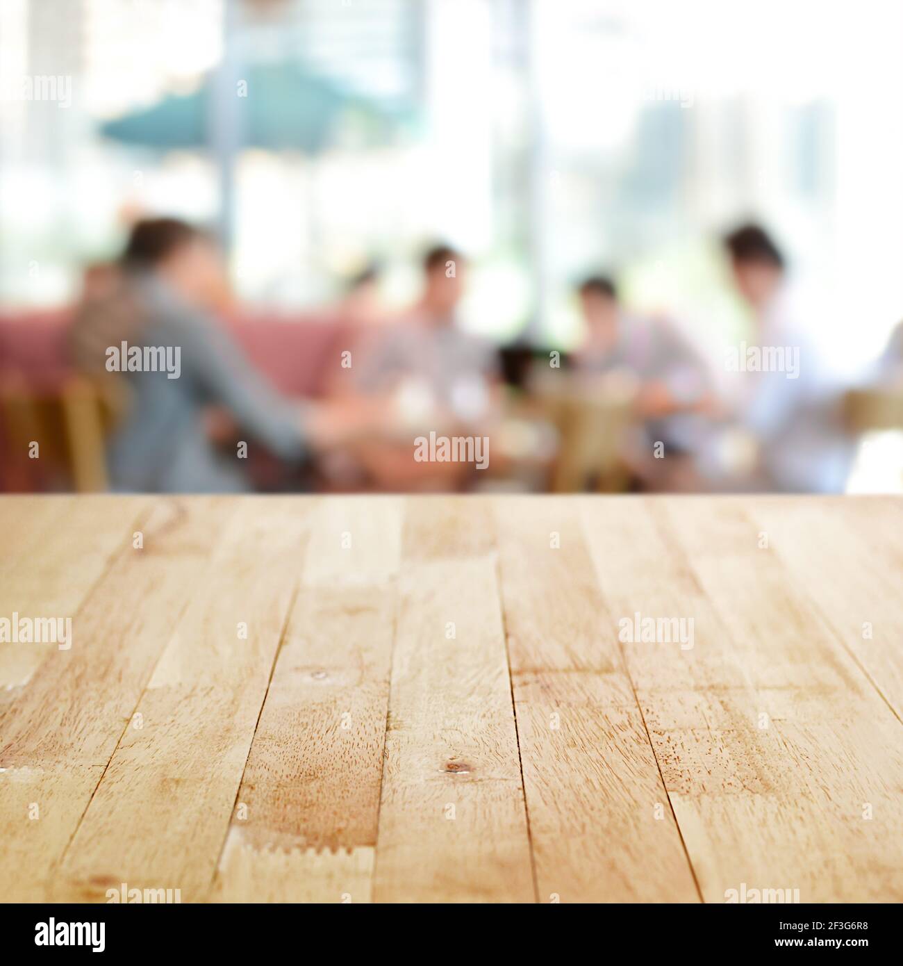 Holztischplatte mit verschwommenen Menschen im Café als Hintergrund - kann zur Montage oder Anzeige Ihrer Produkte verwendet werden Stockfoto