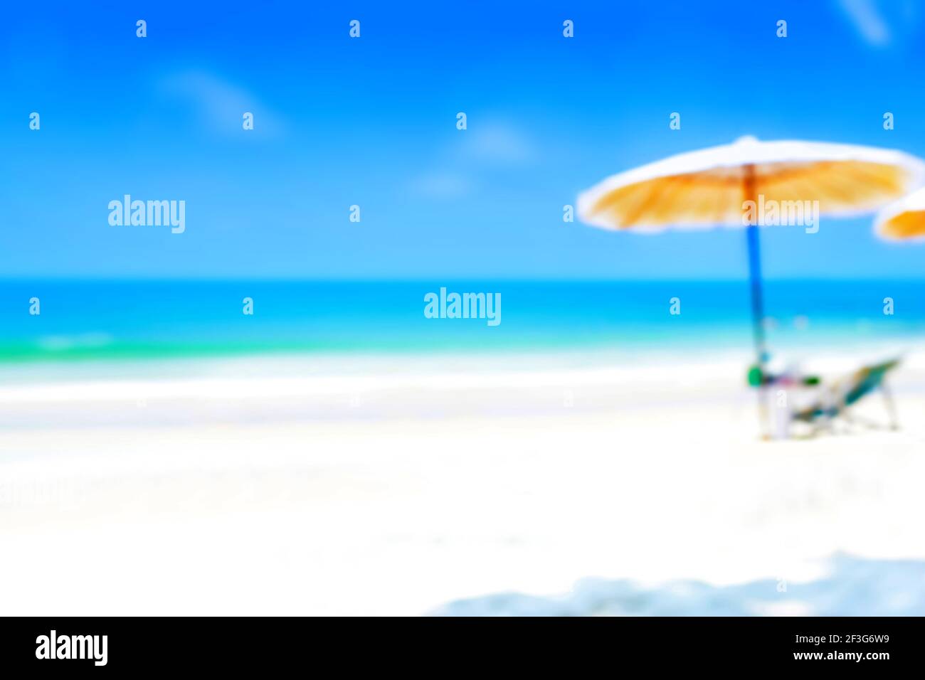 Verschwommenes blaues Meer und weißer Sandstrand mit Sonnenschirm und Strandstuhl - Sommerhintergrund Konzept (mit Kopierraum) Stockfoto