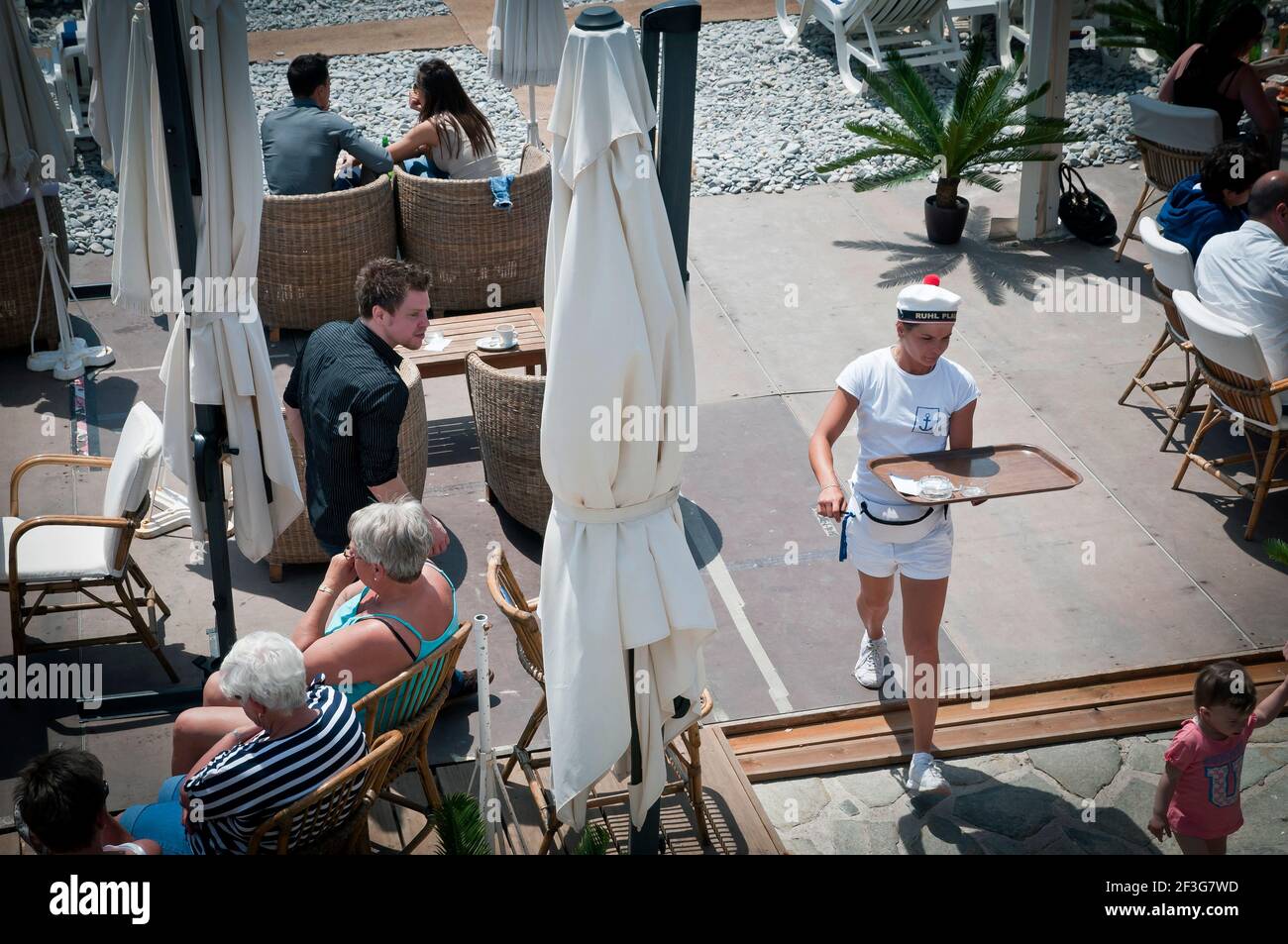 Nette Kellnerin mit einem Tablett serviert Gäste in einem Restaurant am Meer, Nizza, Französisch Riviera, Frankreich Stockfoto