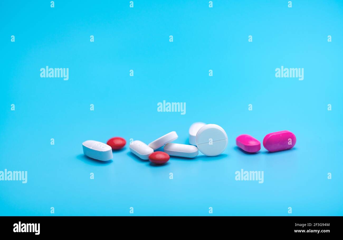 Weiße und rosa Tabletten Pillen auf blauem Hintergrund. Apothekenbanner. Pharmaindustrie. Strategie der Krankenversicherung. Pharmazeutische Fertigung. Stockfoto