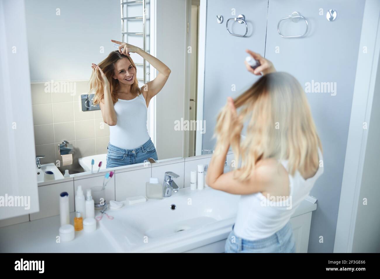 Fröhliche junge Frau mit Haarspray im Badezimmer Stockfotografie - Alamy