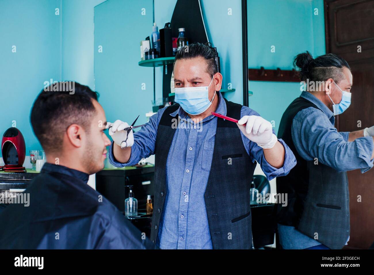 latein Mann Stylistin mit Gesichtsmask schneiden Haare zu einem Kunden In  einem Friseurladen in Mexiko-Stadt in Coronavirus-Pandemie Stockfotografie  - Alamy