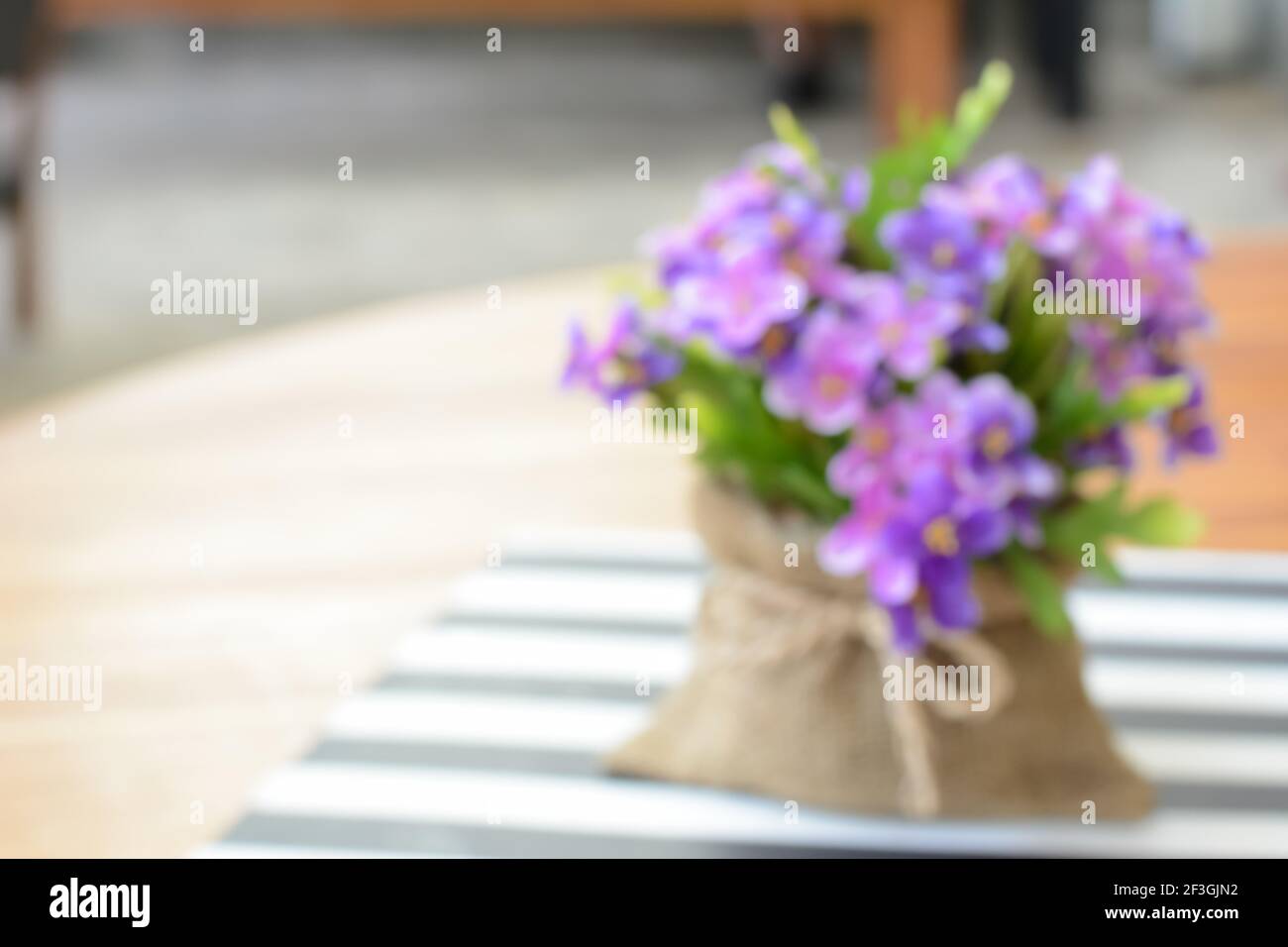Kleine lila Blüten in Jute-Tasche auf dem Tisch - Kann als unscharfer Hintergrund ohne Fokus verwendet werden Stockfoto