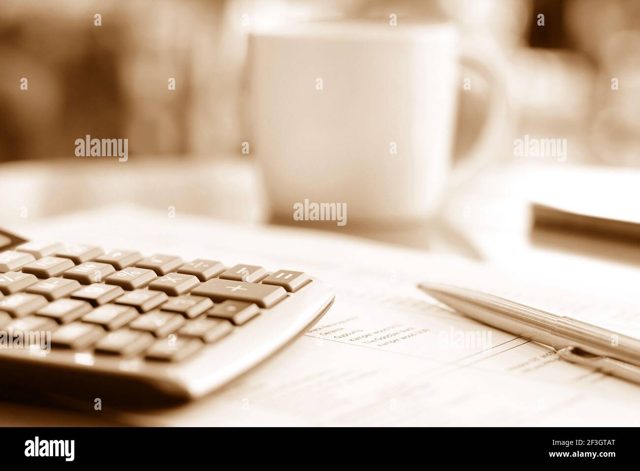 Taschenrechner & Stift über Papier auf dem Tisch mit Unschärfe Kaffeetasse Hintergrund in braun Sepia-Effekt - weicher Fokus Stockfoto