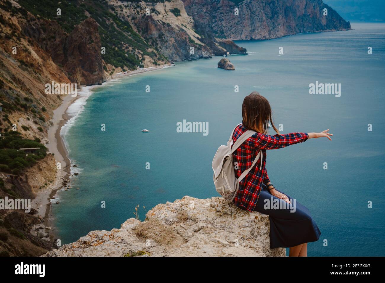 Frau mit Rucksack Touristen am Meer . Genießen Sie schöne Wolken Himmel unter Mighty Cliffs Meeting Ocean. Die Idee und das Konzept der Freiheit, Urlaub ein Stockfoto