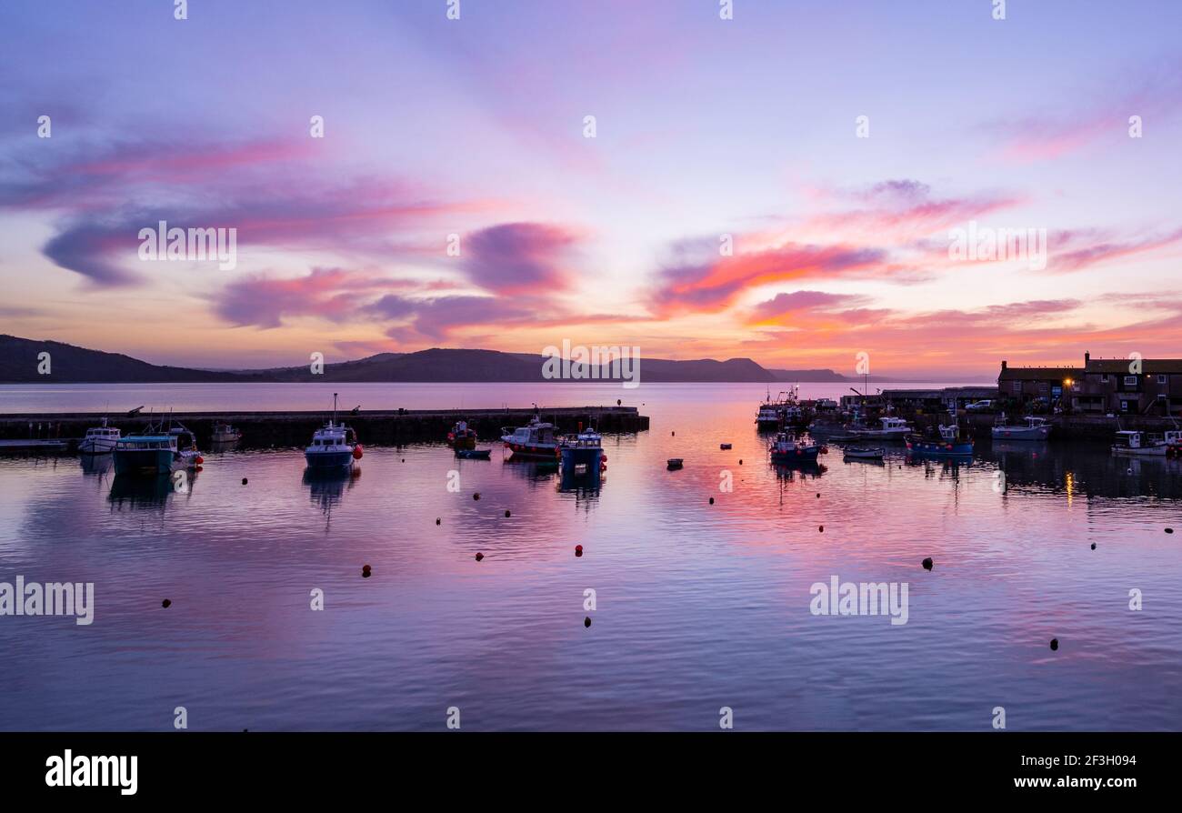 Lyme Regis, Dorset, Großbritannien. März 2021, 17th. UK Wetter: Spektakuläre Sonnenaufgangsfarbe über dem Cobb bei Lyme Regis zu Beginn eines schönen Frühlingstages. Kredit: Celia McMahon/Alamy Live Nachrichten Stockfoto