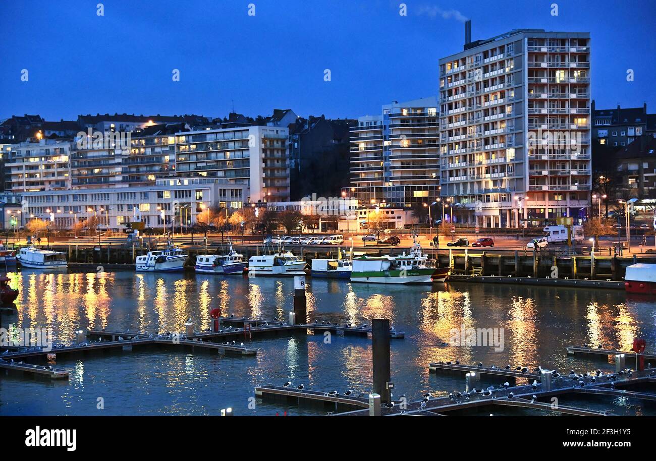 Boulogne-sur-Mer (Nordfrankreich): Fischerboote entlang des Kais im Hafen und nachts beleuchtete Gebäude entlang der „cote d’Opale“-Küste Stockfoto