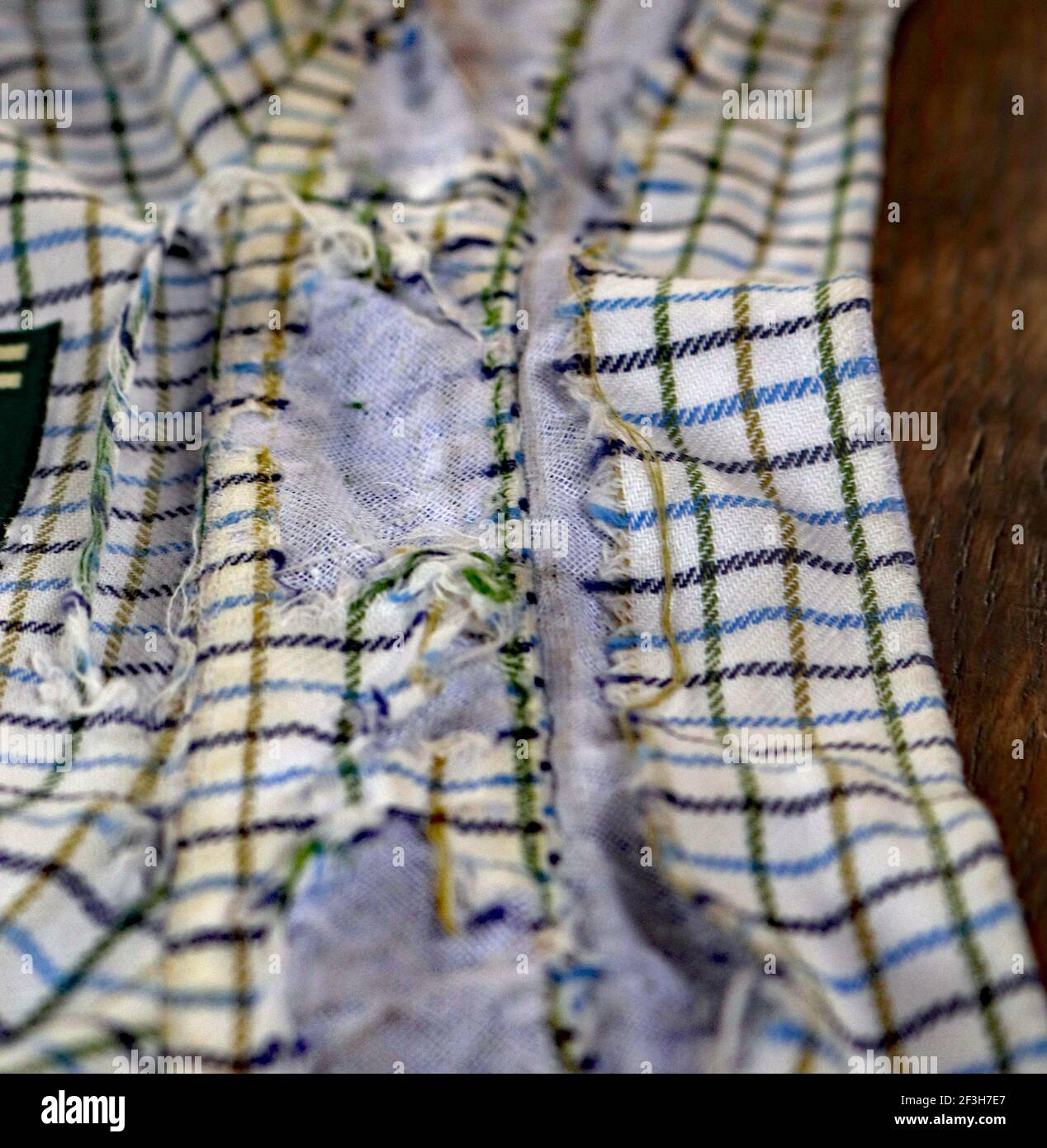 Ein altes, sehr geliebtes Hemd hat das Ende seiner Nutzungsdauer erreicht. Das Baumwollmaterial, aus dem das Hemd hergestellt wurde, ist abgenutzt und abgenutzt. Stockfoto