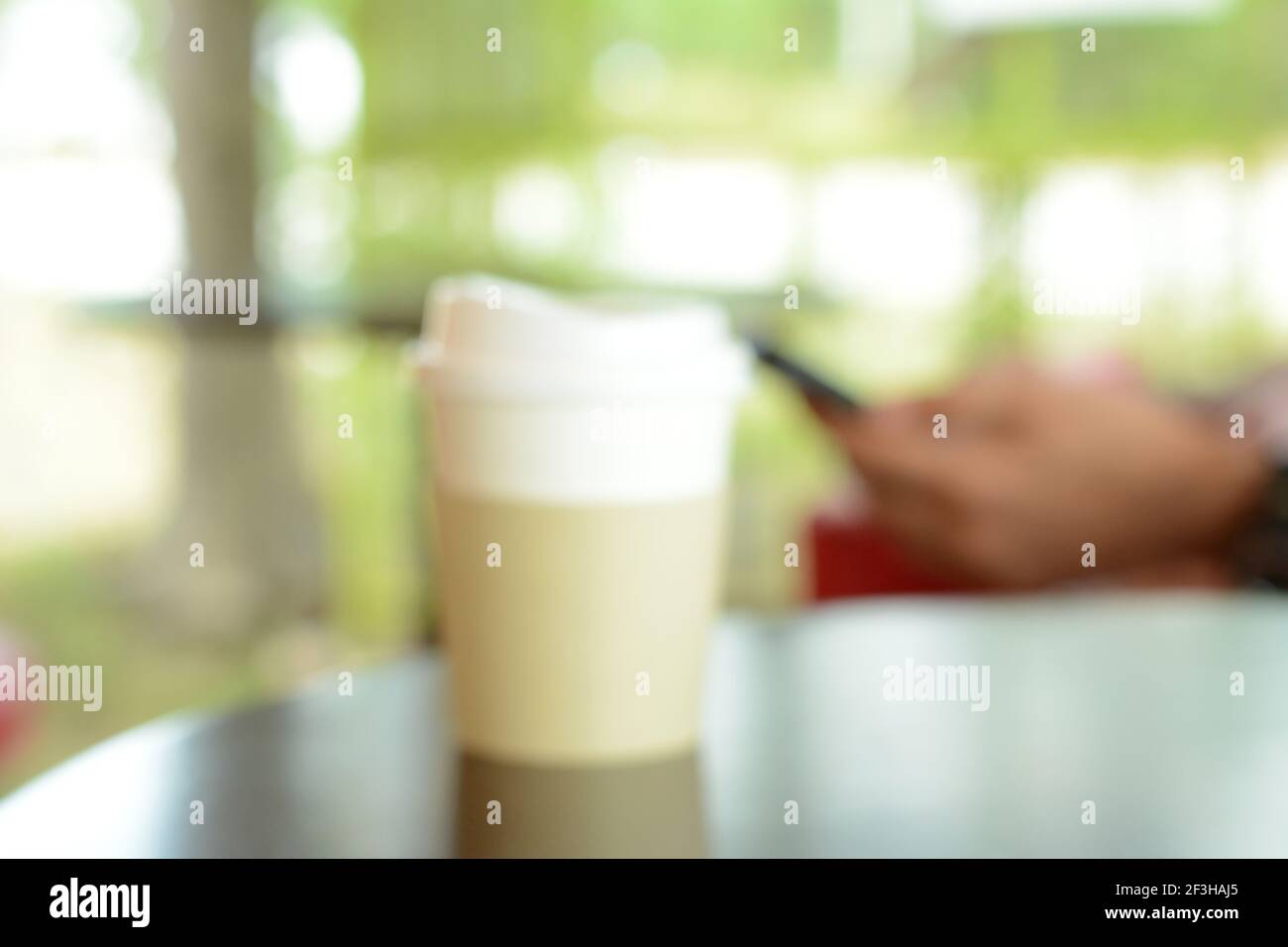Verschwommener Hintergrund der Kaffeetasse zum Mitnehmen auf dem Tisch Im Café Stockfoto