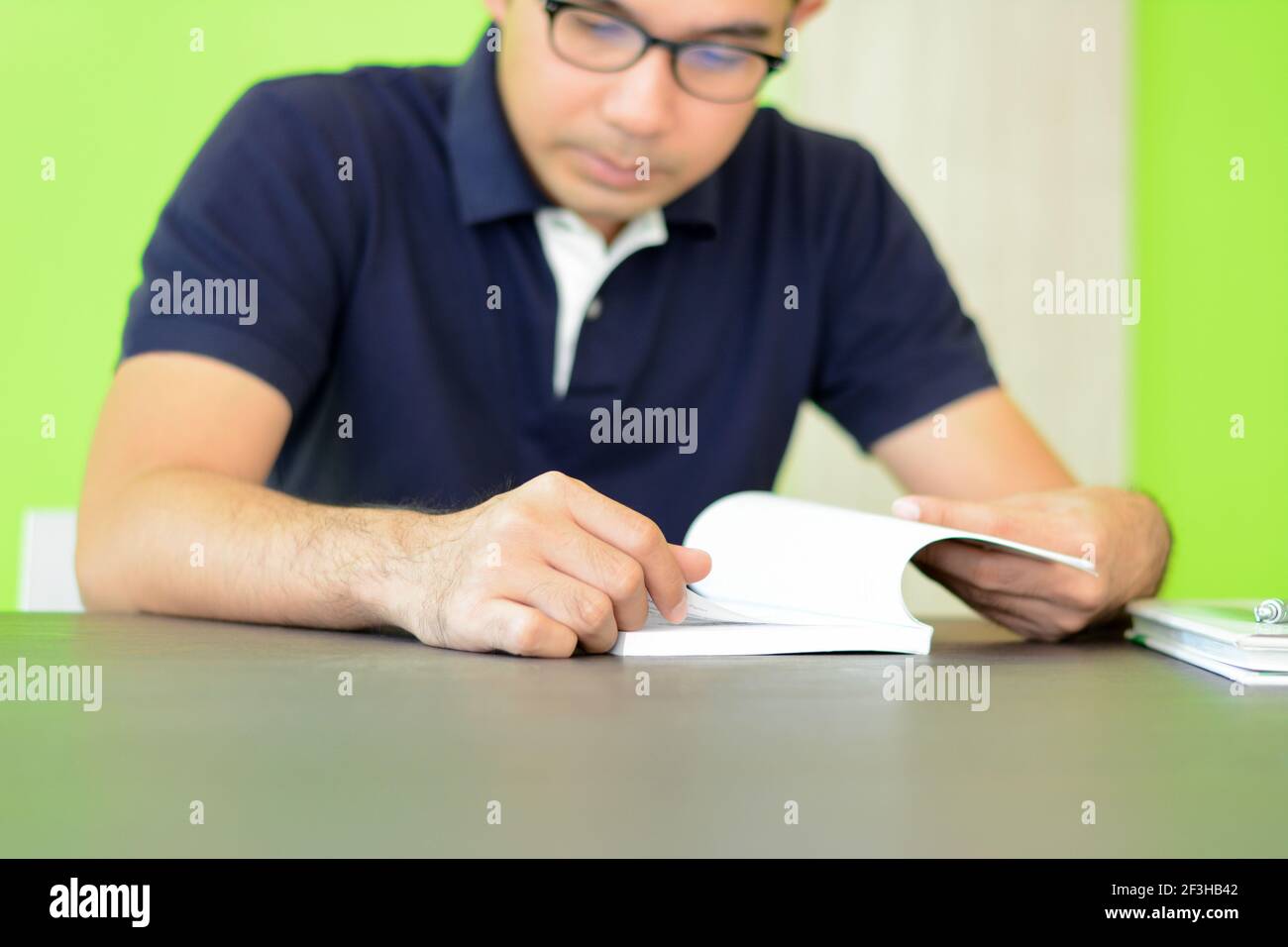 Ein Mann liest Buch auf dem Tisch - Studieren & Prüfungskonzept Stockfoto