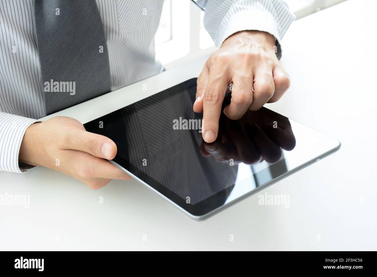 Geschäftsmann mit Tablet-pc auf dem Tisch mit einer Hand Berühren des Bildschirms Stockfoto