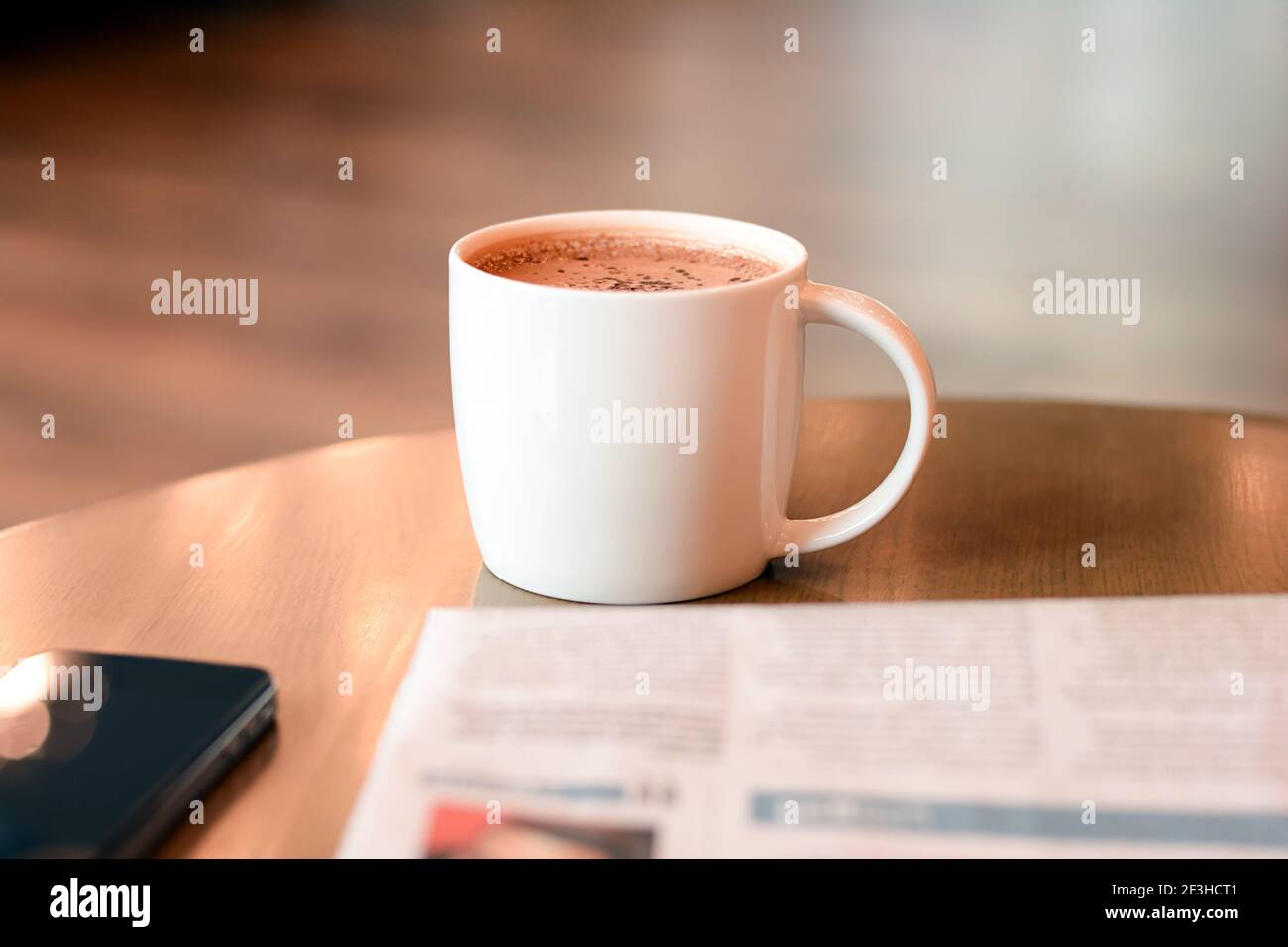 Kaffeetasse mit Zeitung und Handy auf Holztisch Stockfoto