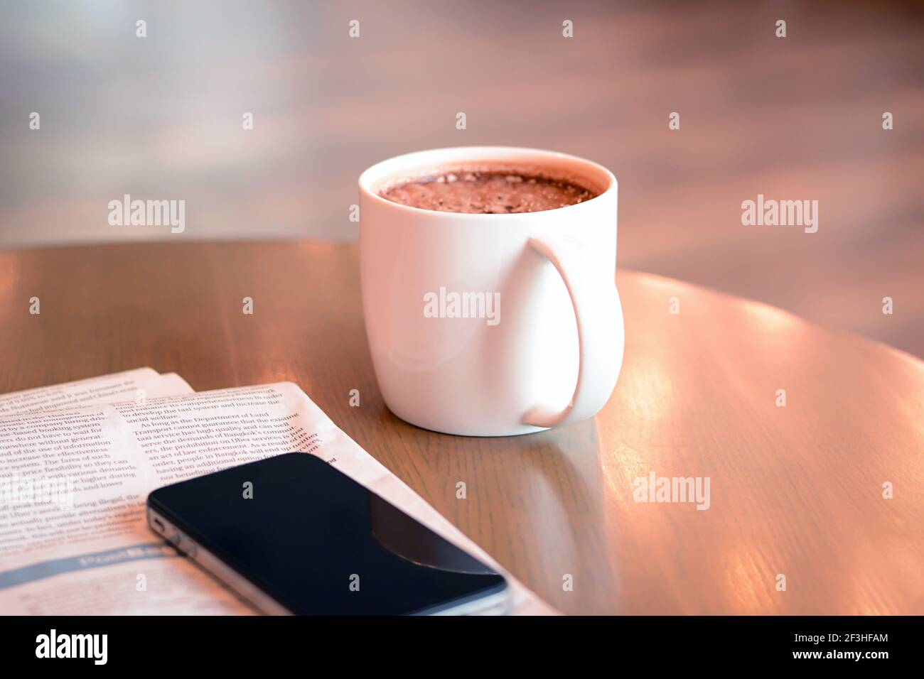 Kaffeetasse mit Zeitung und Handy auf Holztisch Stockfoto