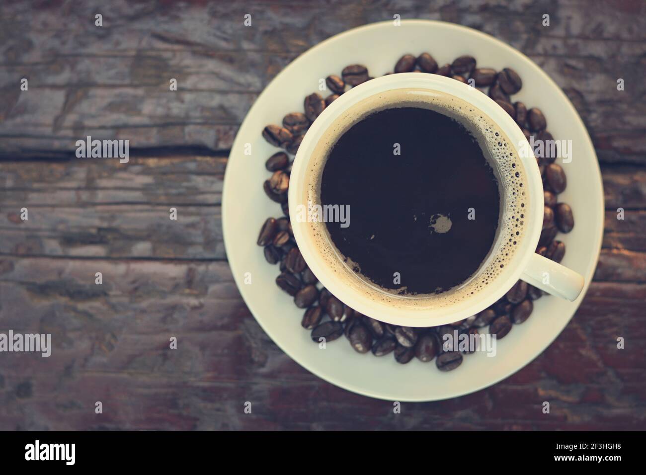 Schwarzer Kaffee in der Tasse auf altem Holztisch (Draufsicht) - Vintage-Farbeffekt Stockfoto