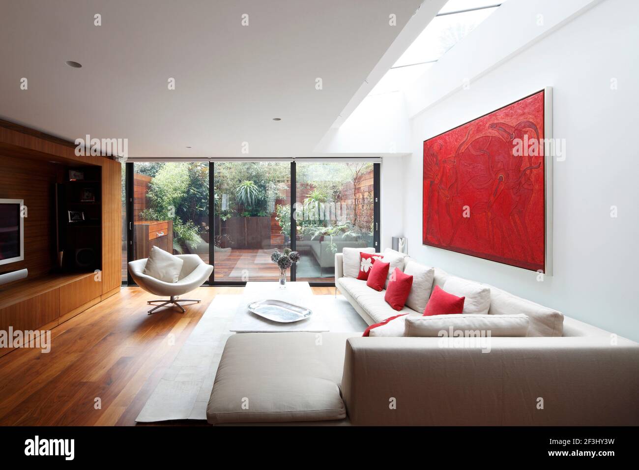 Modernes Wohnzimmer mit verglasten Türen zum Garten (Licht aus Stockfoto