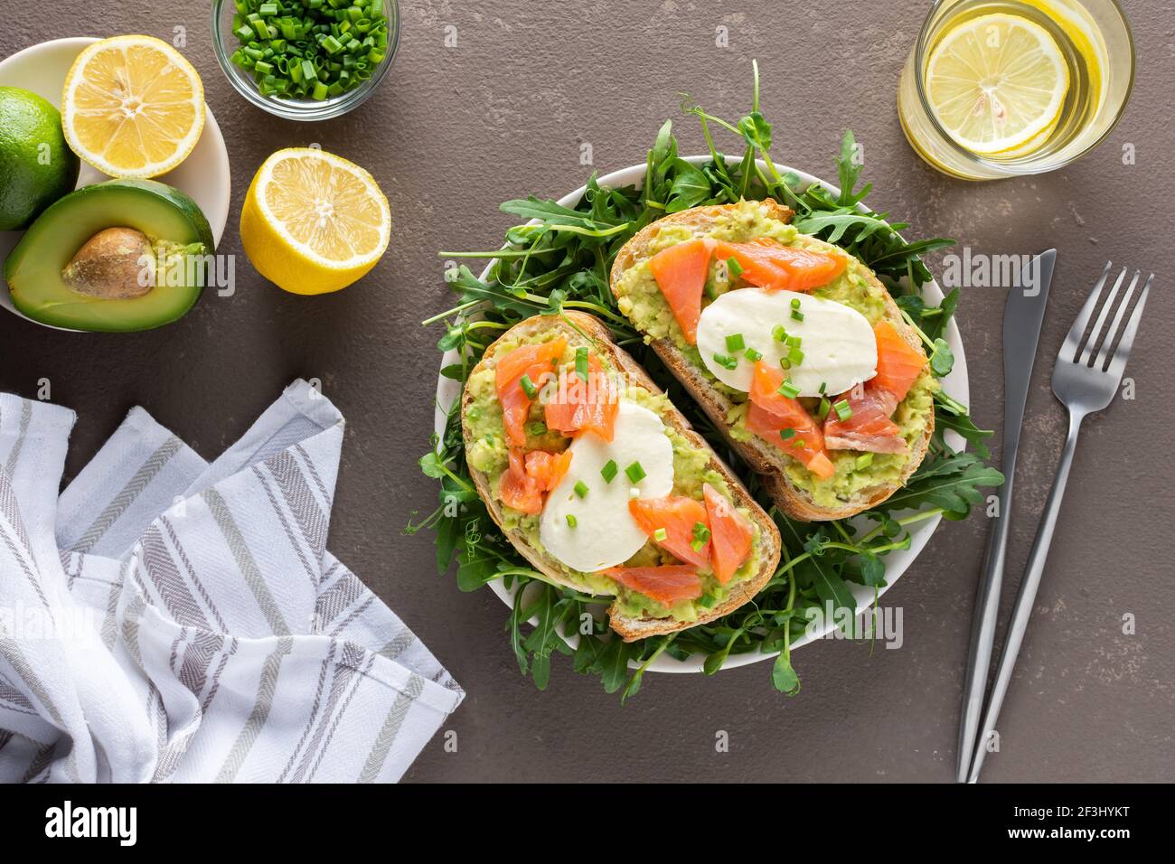 Leckeres herzhaftes Frühstück, Sandwiches mit Avocado-Paste, Lachs und Mozzarella auf einem Teller mit Rucola und Erbsensprossen Stockfoto