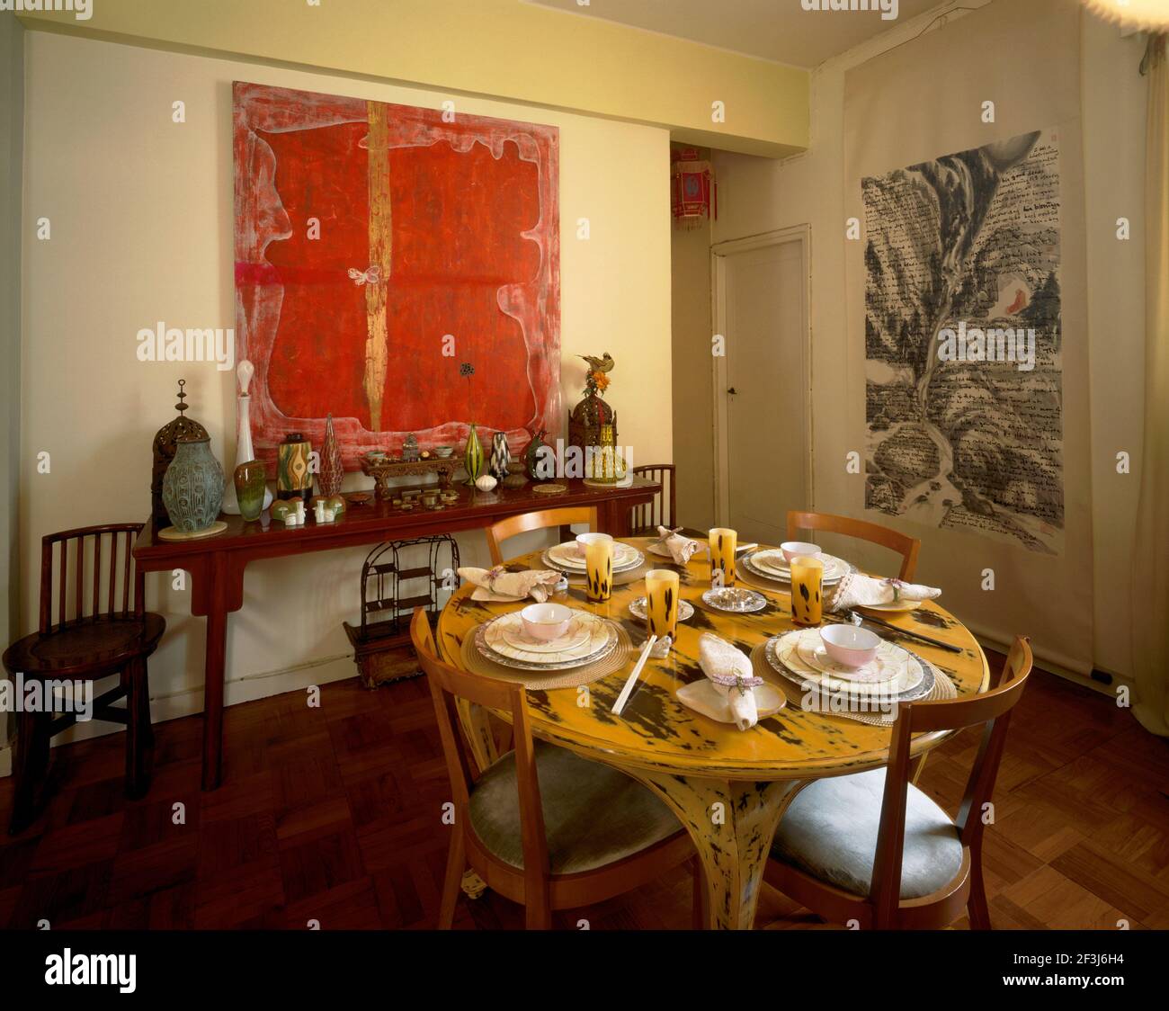 Esszimmer mit Tisch und Stühlen von Gio Ponti. Auf dem Altartentisch befindet sich eine Sammlung von farbigen Glaswaren aus Deutschland neben westlichen chinesischen Stilen Stockfoto