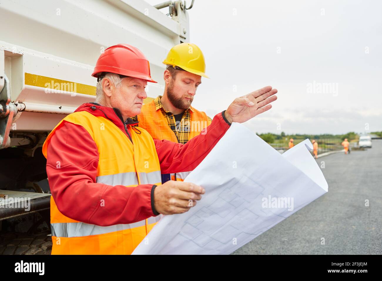 Architekt und Vorarbeiter mit Lageplan für die Entwicklung in Der neue Gebäudebereich vor dem LKW Stockfoto