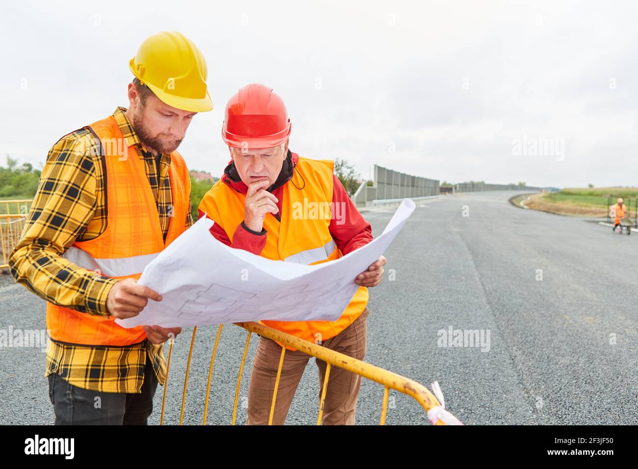 Architekt und Straßenbaumeister mit einem Lageplan auf dem Baustelle für die neue Umgehungsstraße Stockfoto
