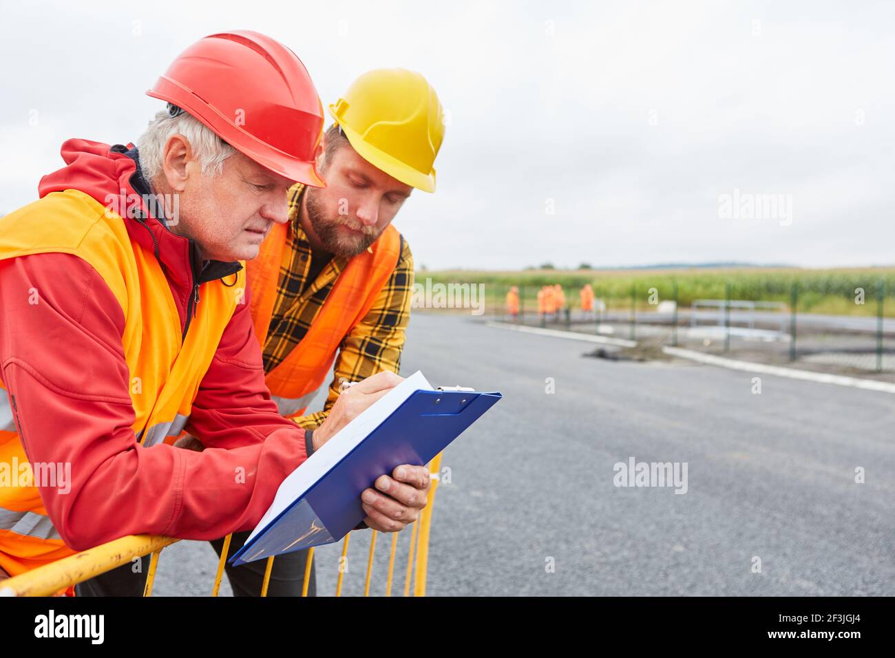 Zwei Bauarbeiter als Straßenbauer mit einer Checkliste für Die Entwicklung eines neuen Gebäudebereichs Stockfoto