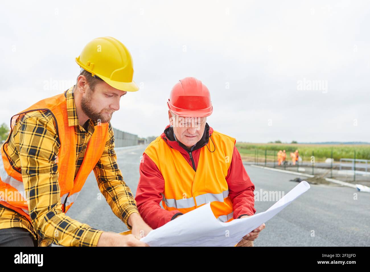 Architekt und Bauarbeiter mit Bauzeichnung für den Hausbau Auf der Baustelle im Neubaugebiet Stockfoto