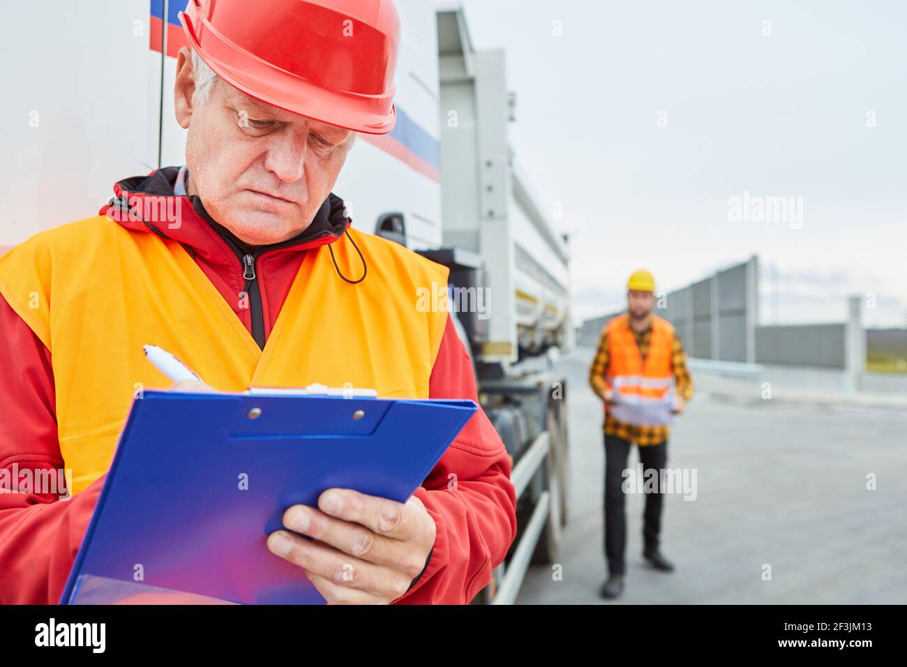 Der Vorarbeiter überprüft anhand der Checkliste eine Materiallieferung Zur Baustelle Stockfoto