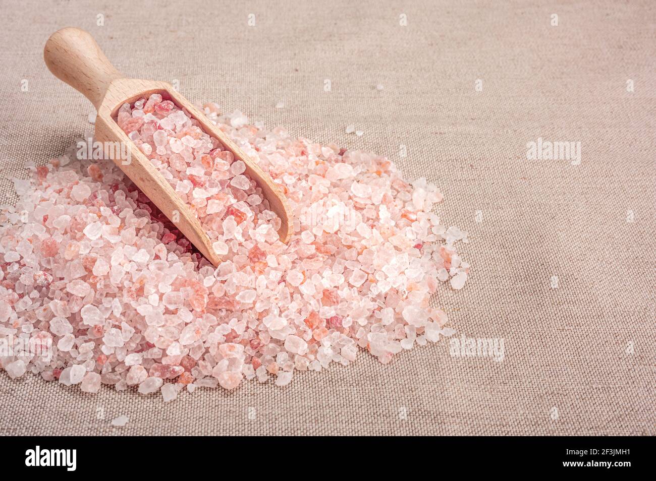 Rosa himalaya-Salz. Holzlöffel mit rosa himalaya-Salz auf Textil-Sackleinen Hintergrund. Himalaya-Salzhaufen. Kopieren Raum Stockfoto