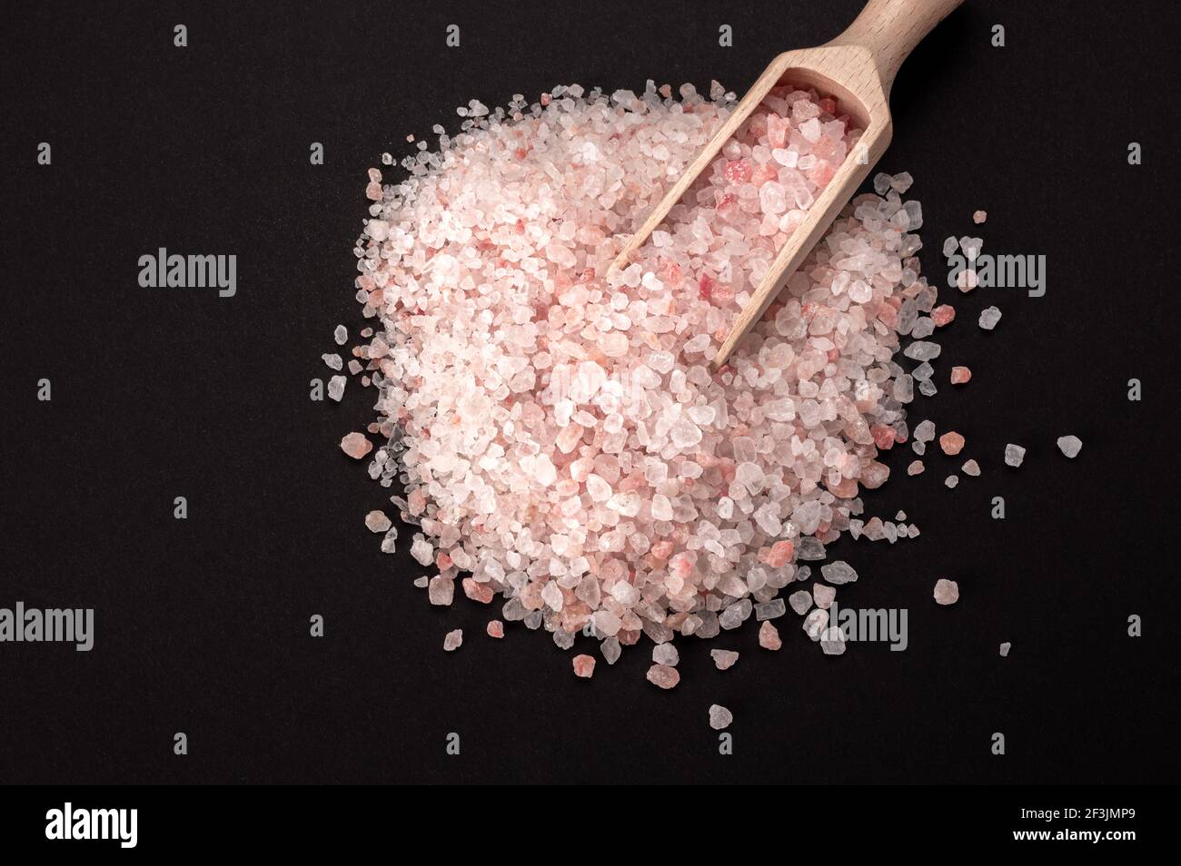 Rosa himalaya-Salz. Himalayan Pink Rock Salt in Holzlöffel auf schwarzem Hintergrund. Draufsicht. High Angle View Of Himalayan Salt Mit Holzlöffel Auf Ta Stockfoto