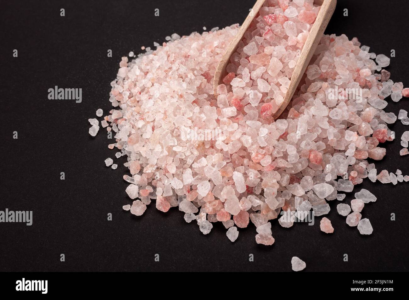 Rosa himalaya-Salz. Himalayan Pink Rock Salt in Holzlöffel auf schwarzem Hintergrund. Draufsicht. High Angle View Of Himalayan Salt Mit Holzlöffel Auf Ta Stockfoto