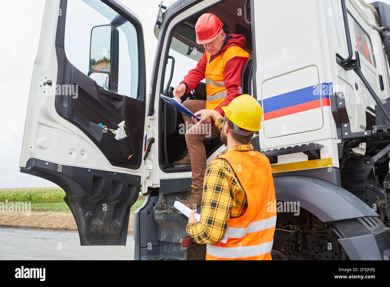 Arbeiter überprüft LKW-Fahrer mit einer Lieferung für die Konstruktion Baustelle im Straßenbau Stockfoto