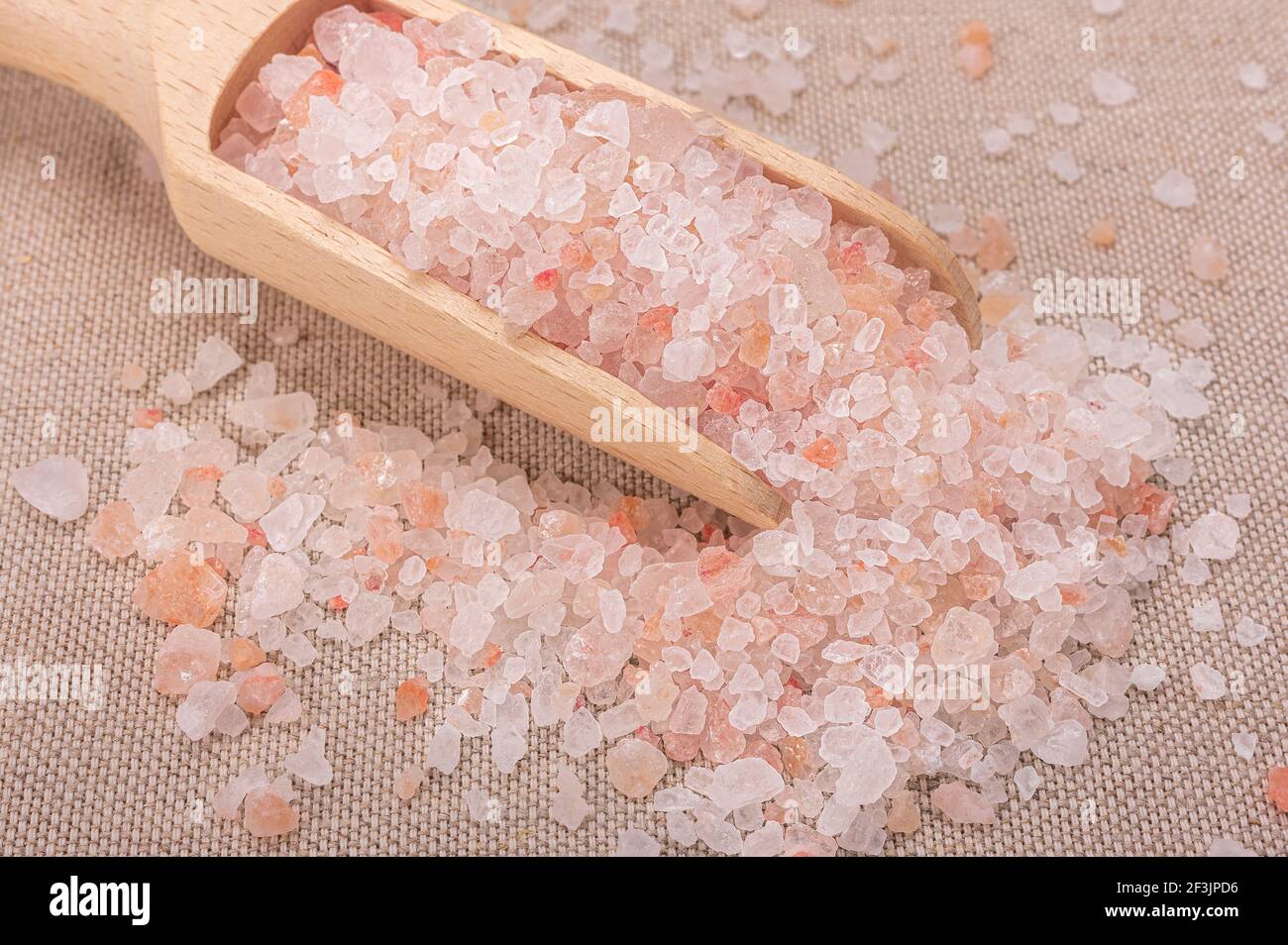 Rosa himalaya-Salz. Nahaufnahme Himalayan Pink Rock Salt in Holzlöffel auf schwarzem Hintergrund. Draufsicht. High Angle View Of Himalayan Salt With Wooden Sp Stockfoto