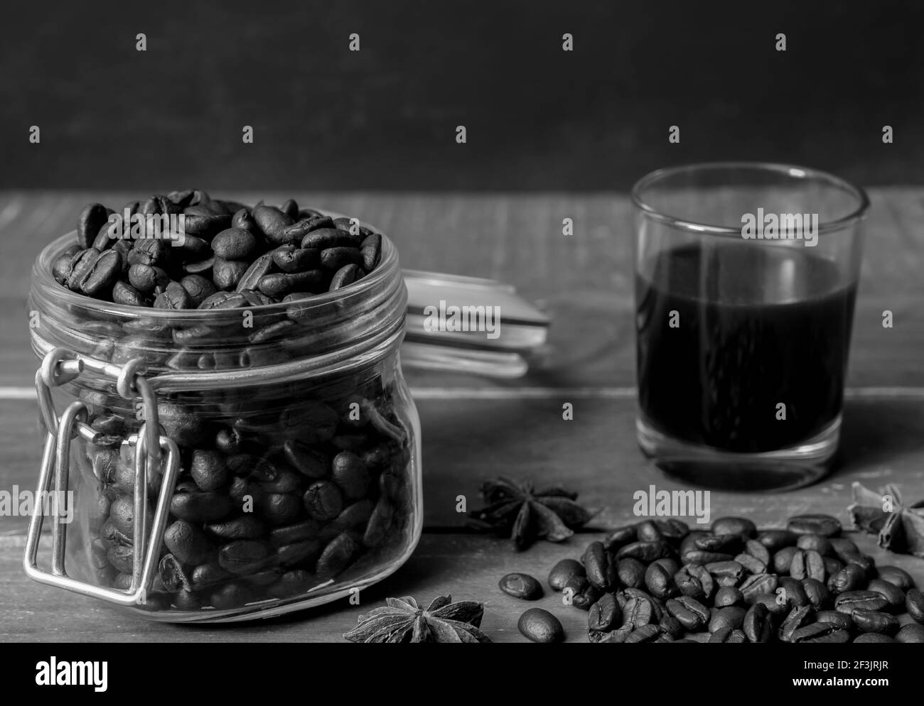 Schwarzer amerikanischer Kaffee im Glas mit Kaffeebohnen im Glas auf rustikalem Holztisch und dunklem Hintergrund. Stockfoto