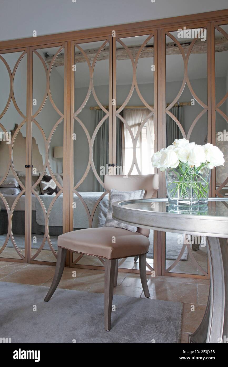 Spiegel gemusterte Schranktüren im Gästeschlafzimmer der St Tropez Villa  mit runder Tisch mit weißen Rosen im Vordergrund. Villa Mit Blick Auf Den  Belleview, St. Tropez Stockfotografie - Alamy