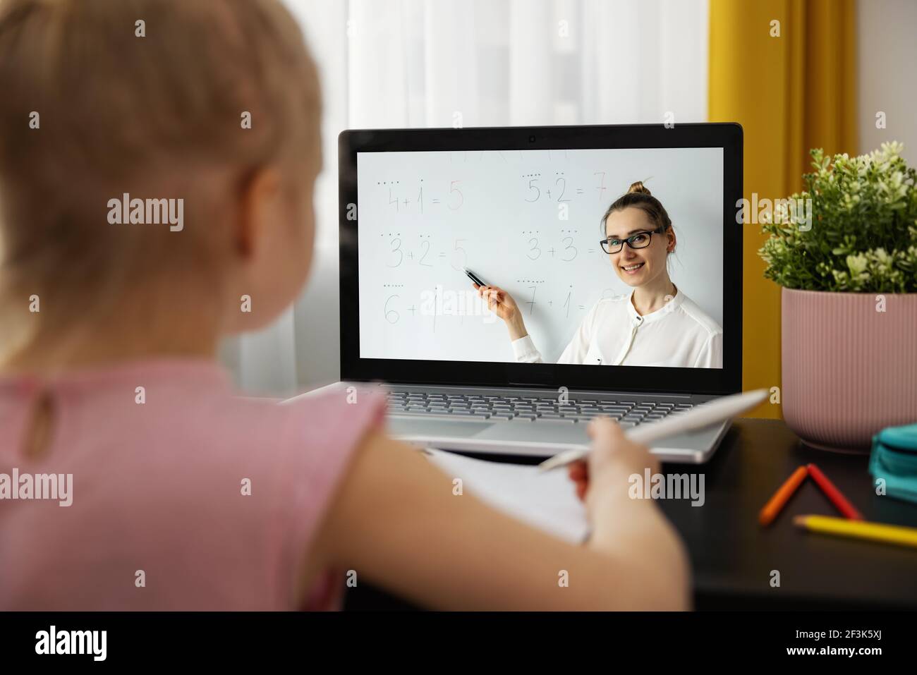 Fernunterricht - Grundschullehrerin erklärt grundlegende Mathematik online. Kleines Mädchen mit Laptop zu Hause. Matheunterricht Stockfoto