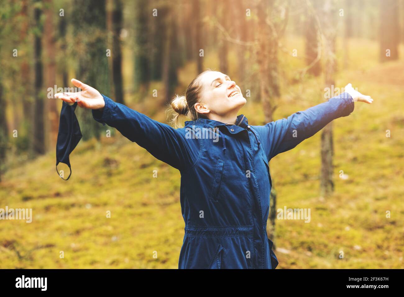 Psychische Gesundheit und Stressabbau während covid-19 Pandemie. Frau genießen Natur und frische Luft mit entfernten Gesichtsmaske im Wald Stockfoto