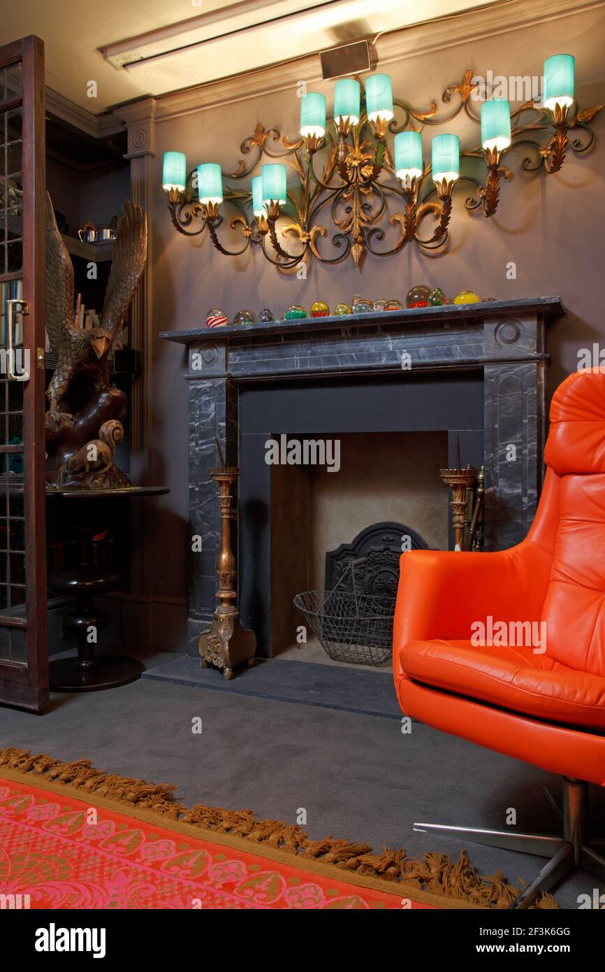 Rotem Leder Drehstuhl und bärtigen Teppich vor dem Kamin aus Marmor Stockfoto