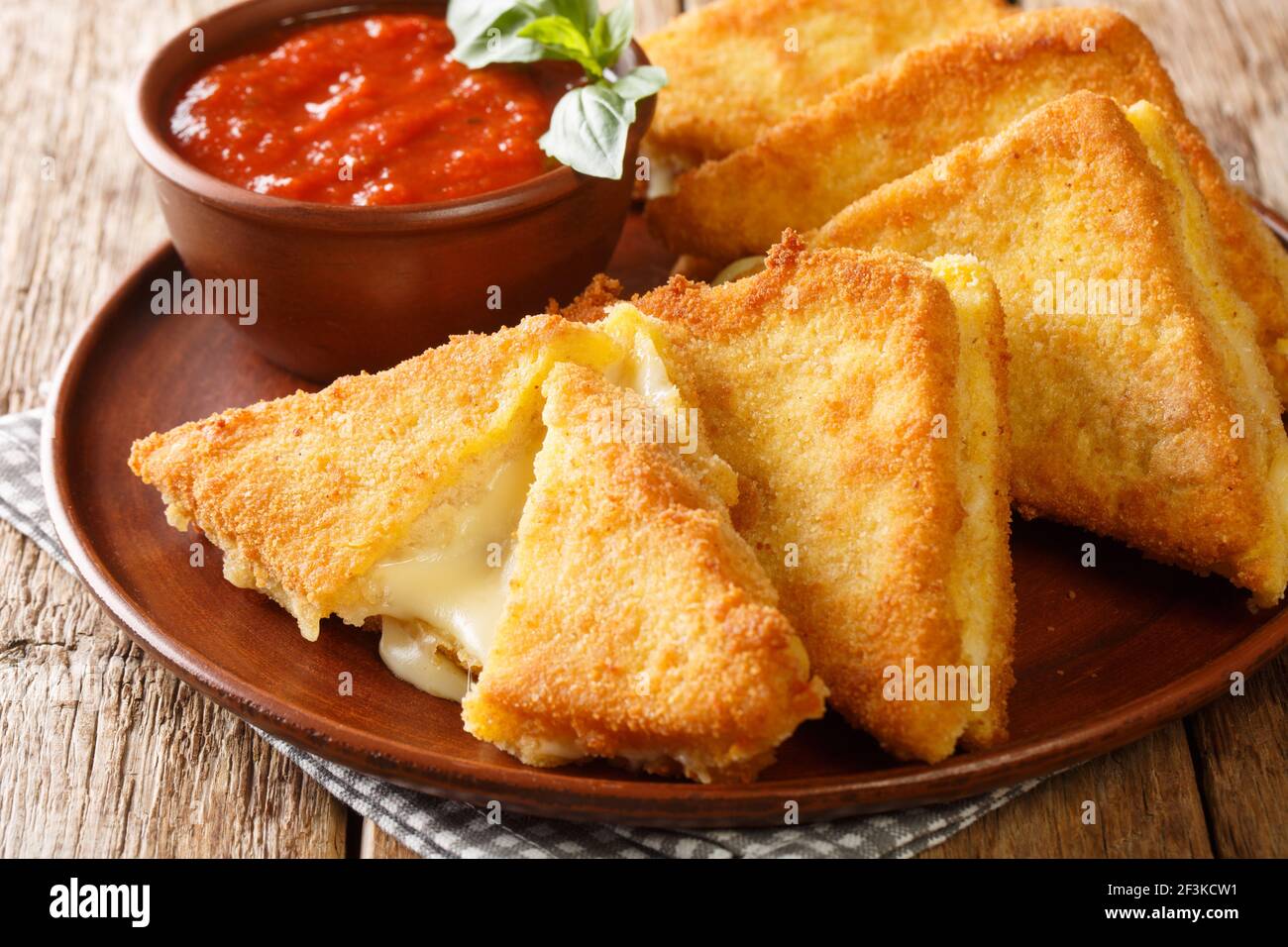 Mozzarella in carrozza besteht aus geschnittenem Brot, das die kostbare Cremigkeit der Mozzarella in der Nähe in der Platte auf dem Tisch umschließt. Horizontal Stockfoto