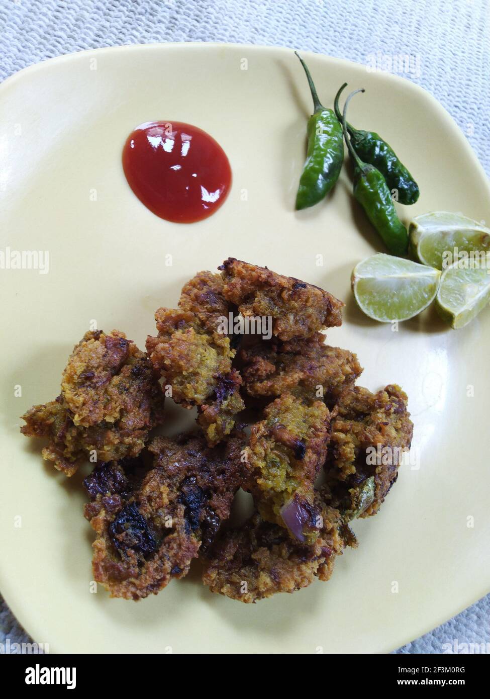 Indische dal pakora Rezept mit Tomatensauce grün kühl und Zitronenstücke auf einem Teller Stockfoto