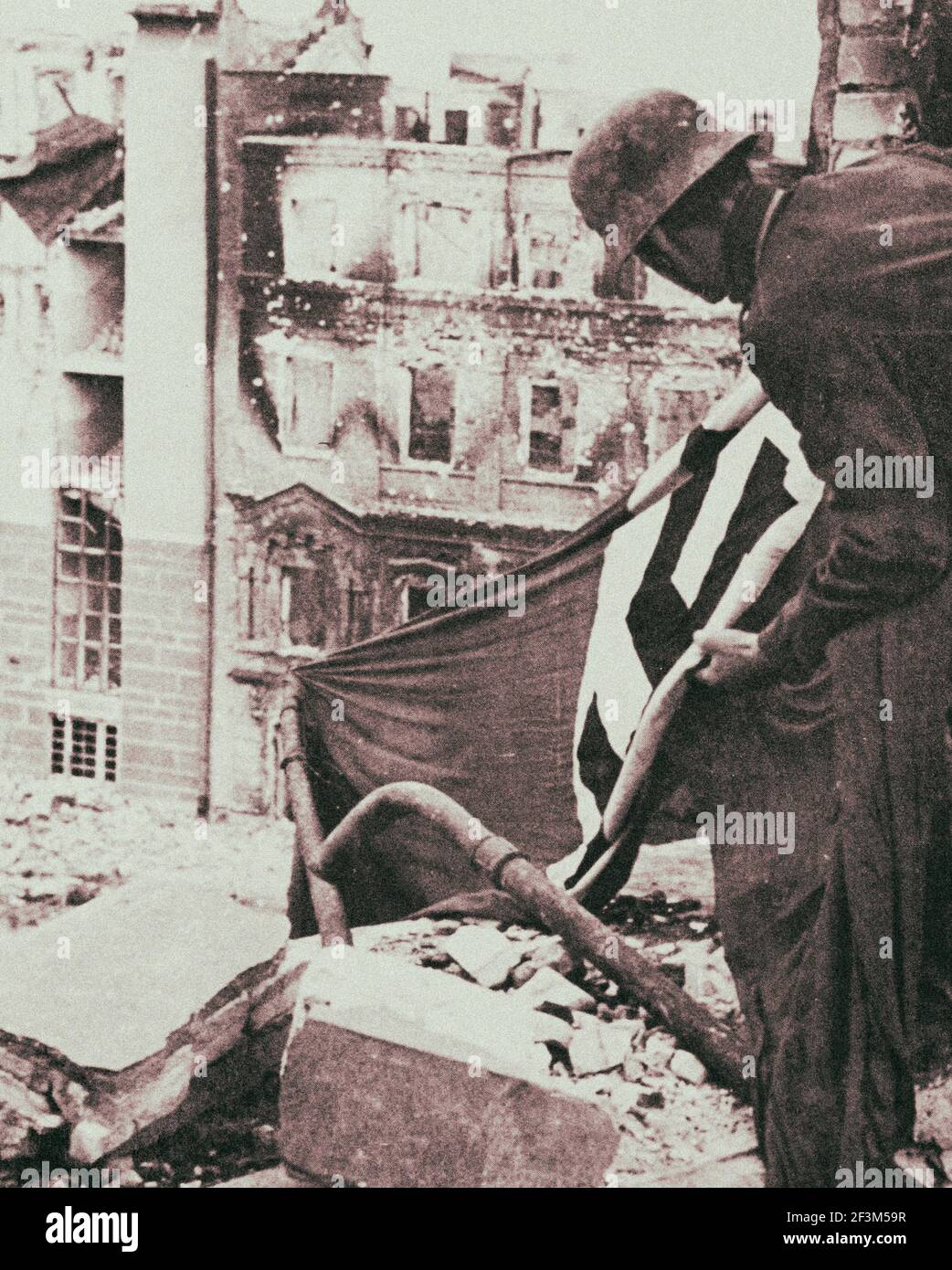 Archivfoto des gefangenen deutschen Soldaten hebt eine Nazi-Flagge aus dem Schutt in Berlin. 1945 Stockfoto