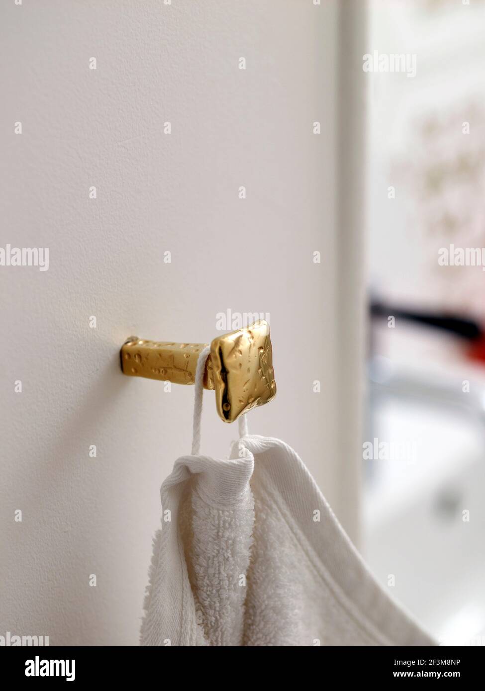 Gold dekorativen quadratischen Handtuch Haken an der weißen Wand in Französisch Wohnung befestigt. Stockfoto