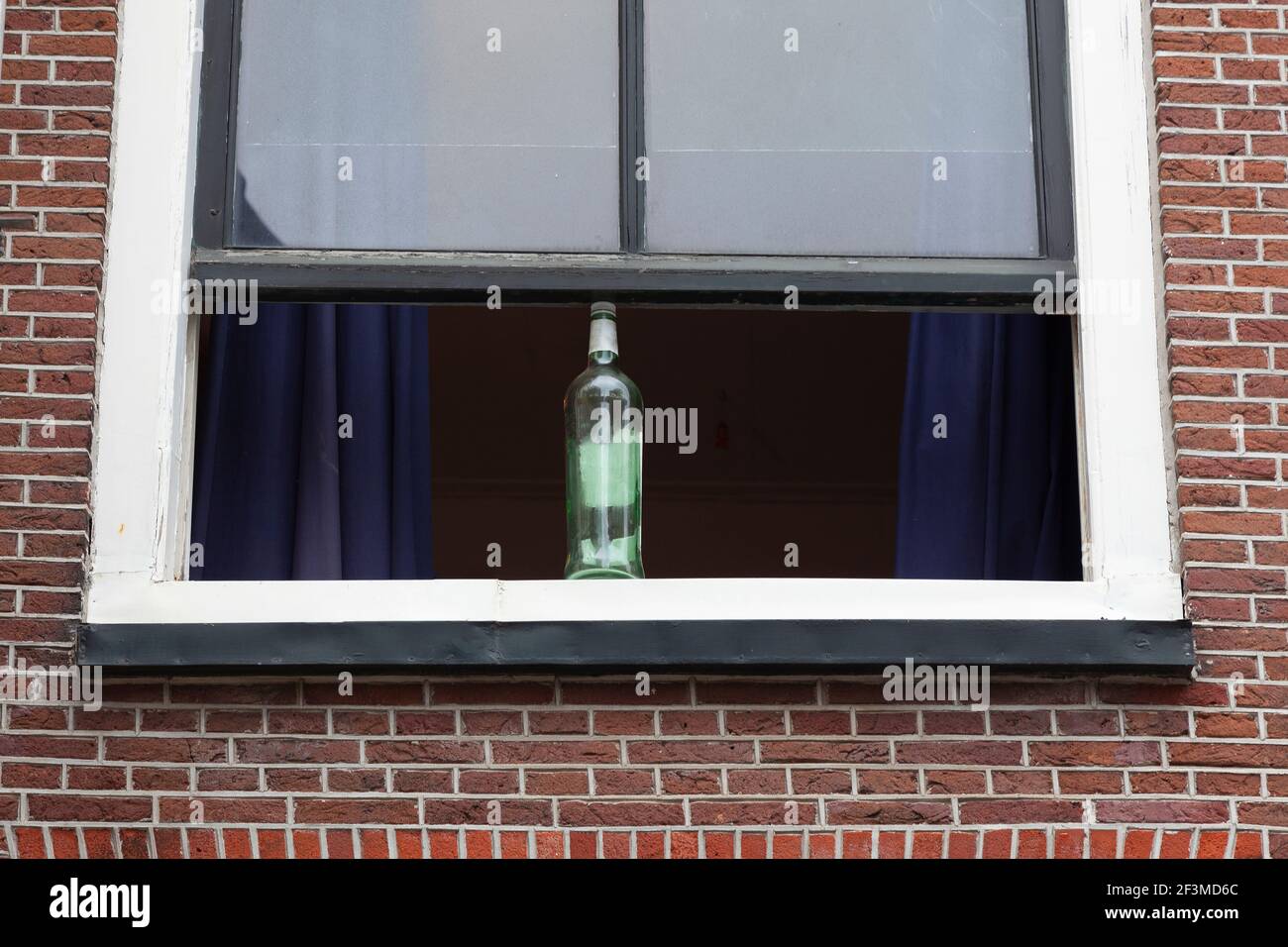 Zweite Verwendung einer leeren Glasflasche, um die zu halten Fenster geöffnet Stockfoto